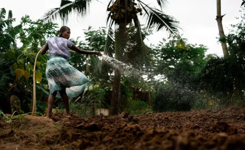 Une jeune tanzanienne arrose un jardin