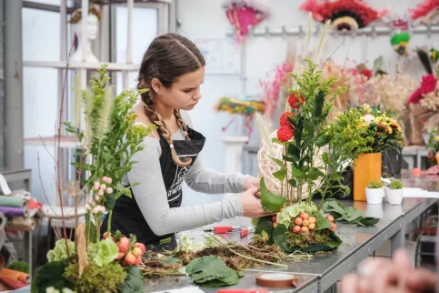 Une jeune en formation en fleuristerie en train de réaliser un bouquet