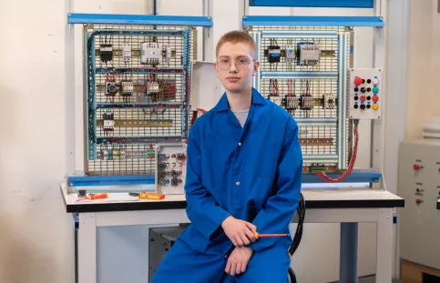 Jeune en formation électricité posant devant son plateau technique de formation
